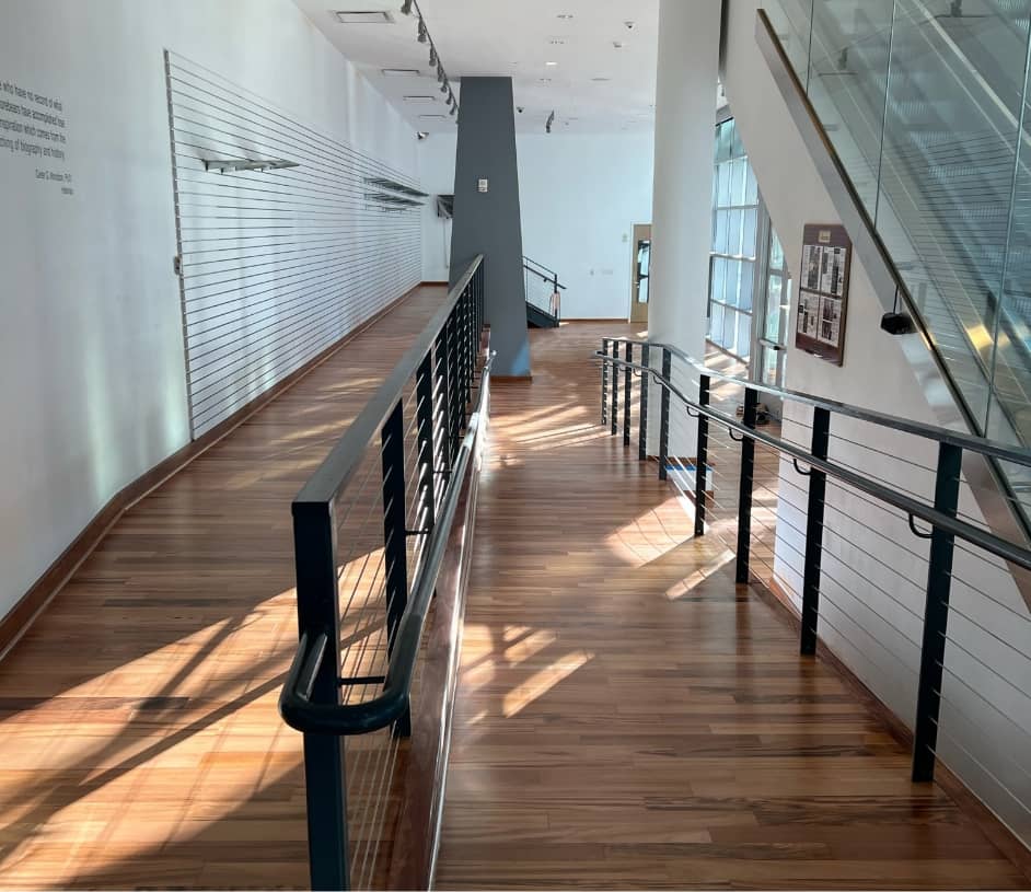 Commercial space with ramp and wood style floor with black metal railiings.