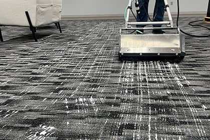 Commercial carpet cleaning machine cleaning a gray carpet.