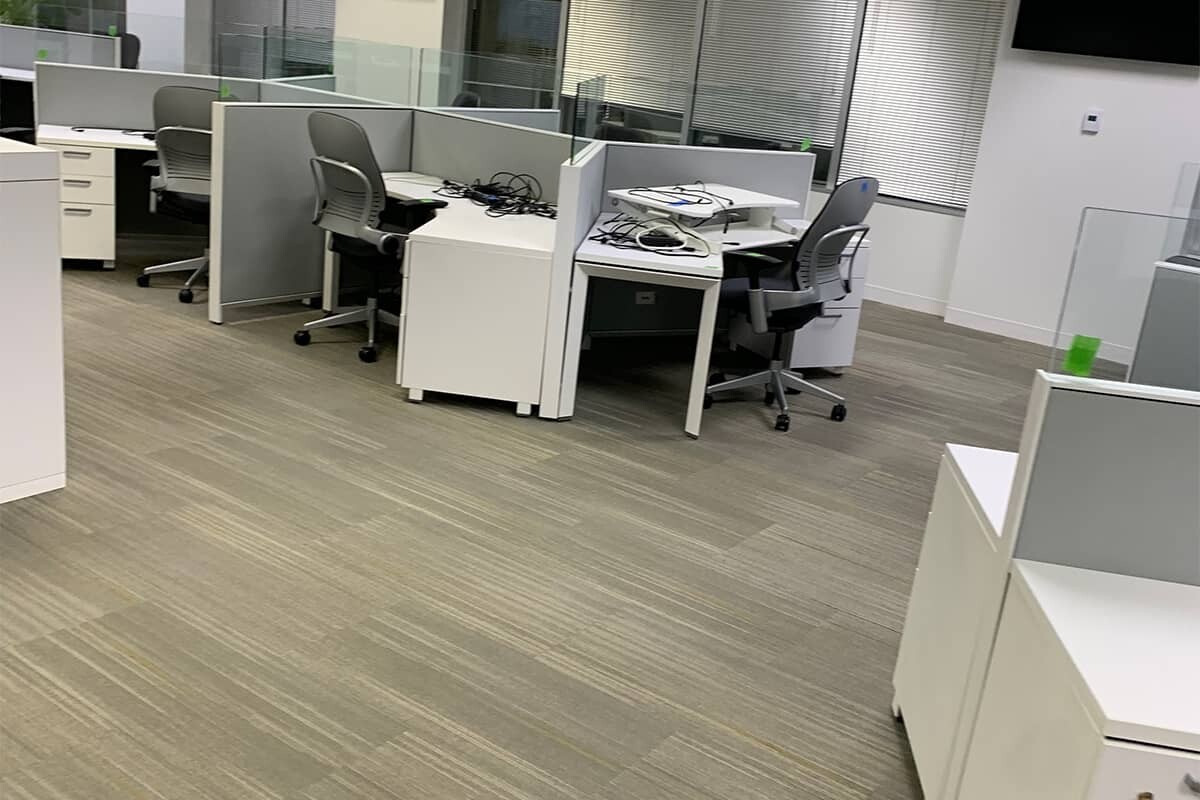Office with cubicles and white walls showing new beige commercial flooring.