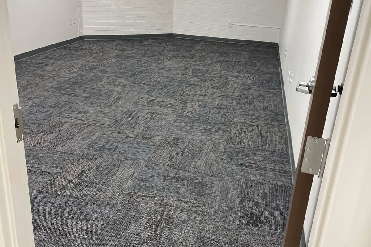 Empty room with gray commercial carpet tiles.