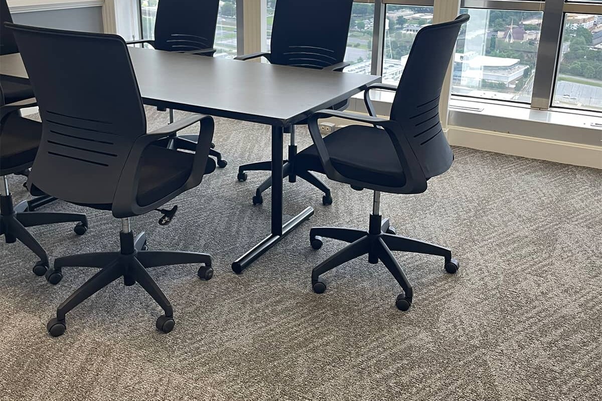 Conference room with table and office chairs on a brown patterned carpet.